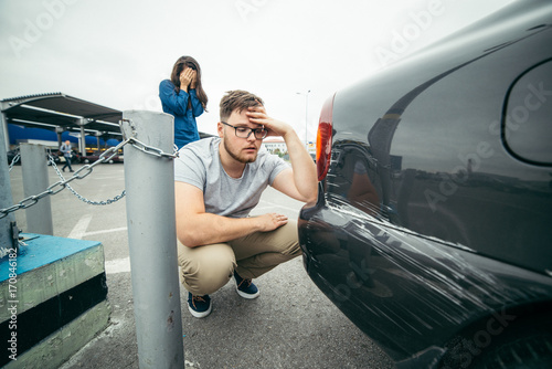 sad man looking on car scratch, woman stand behind him photo