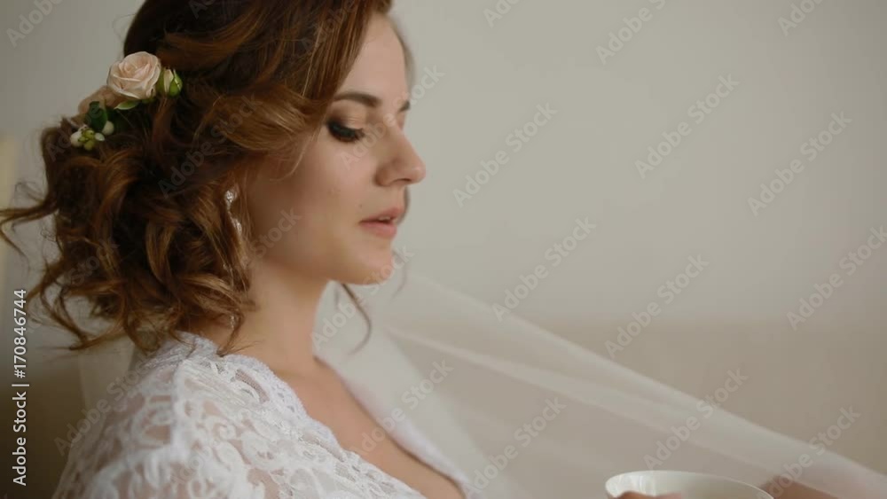 Beautiful caucasian bride drinking tea sitting on the white sofa Beautiful caucasian bride drinking tea sitting on the white sofa