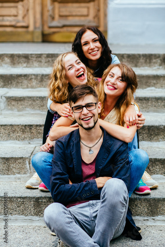 Group of four students sitting on outside on stairs.