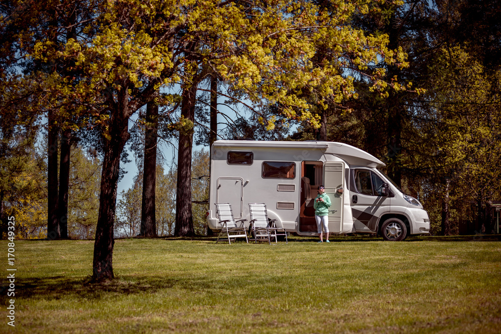 Woman is standing with a mug of coffee near the camper. Woman is standing with a mug of coffee near the camper.