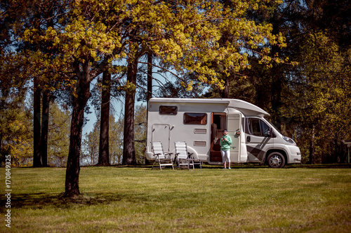Woman is standing with a mug of coffee near the camper.