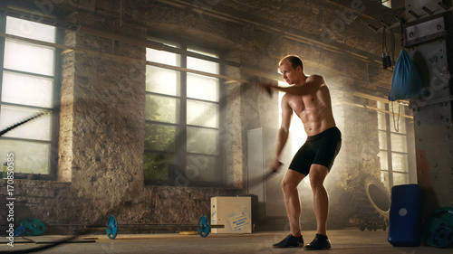 Muscular Shirtless Man in a Gym Exercises with Battle Ropes During His Cross Fitness Workout/ High-Intensity Interval Training.