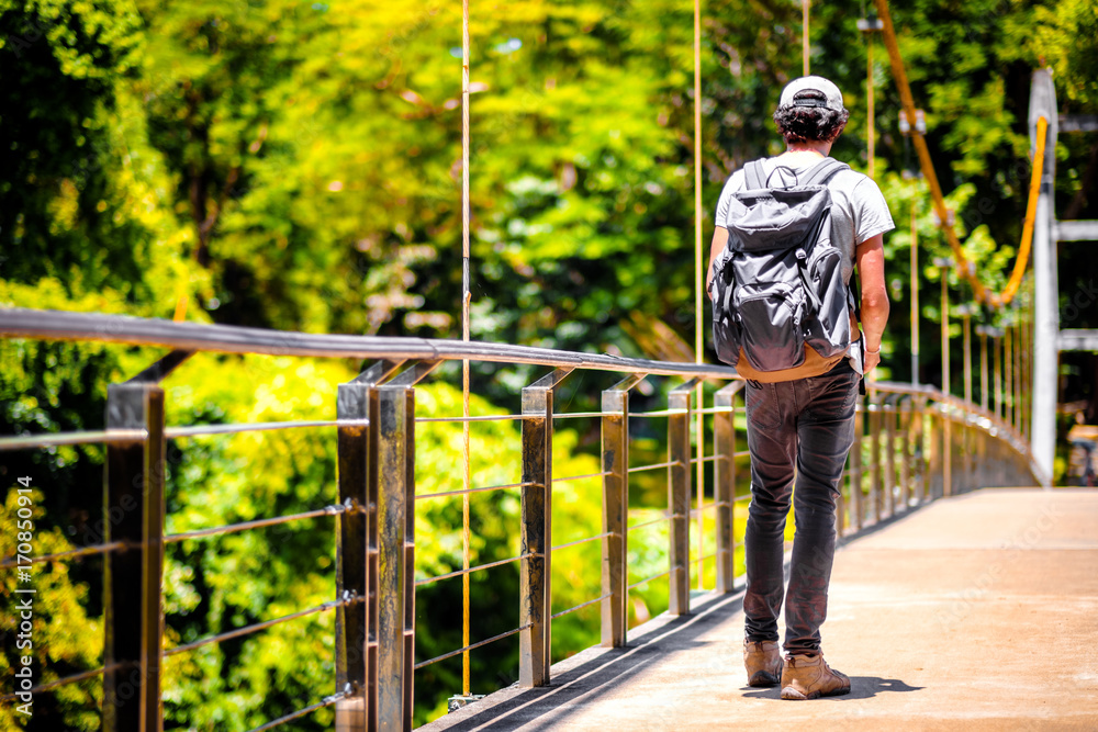 man traveling walking with backpack at national park in the jungle day time sun shine on holiday at weekend relax fresh on background nature view