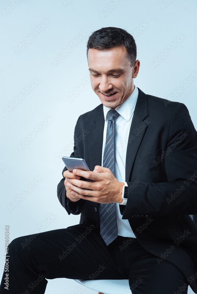 Cheerful delighted man texting a message Cheerful delighted man texting a message