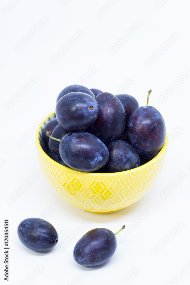Plums in a bowl, separated, close up. White background. Plums in a bowl, separated, close up. White background.