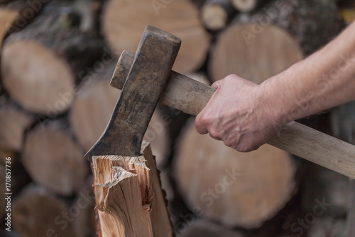 Axe with hand, Heap of chopped wood, close up on the axe, cutting firewood and preparing winter wood