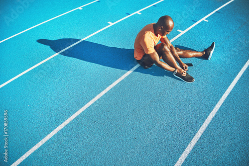 Young athlete tying his shoes while preparing for a run