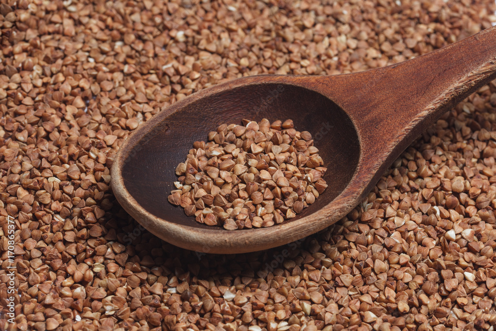 Wooden spoon with buckwheat on the background of buckwhea Wooden spoon with buckwheat on the background of buckwhea