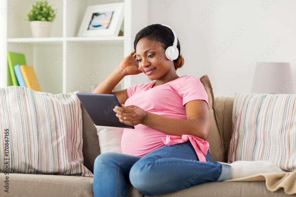 Fototapeta premium pregnant woman in headphones with tablet pc