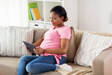 happy pregnant woman with tablet pc at home