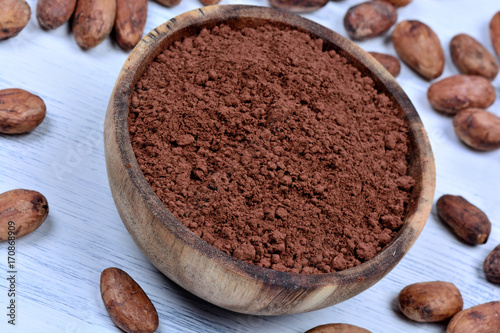 Bowl with cacao powder and beans on table