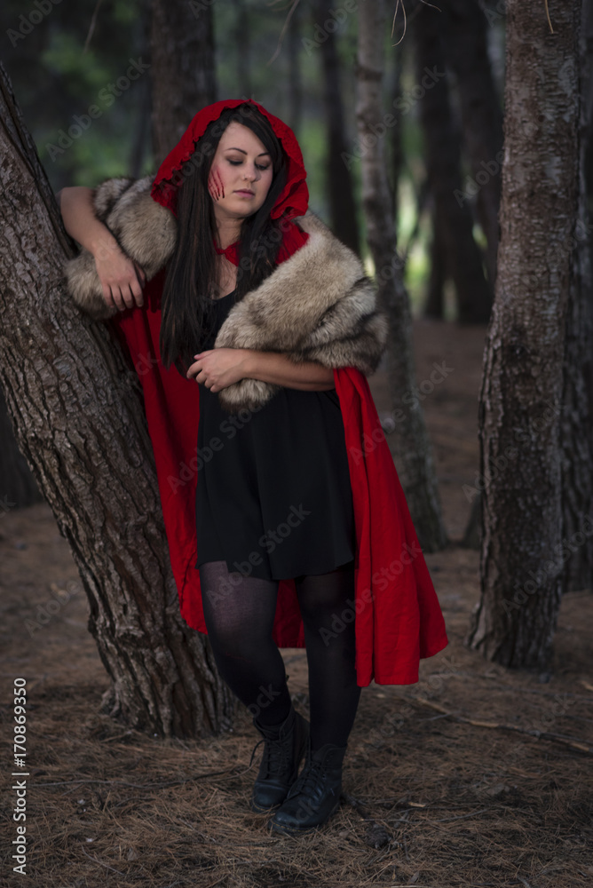 Little Red Riding Hood. A slightly darker take on the character where she  is the evil one hunting the wolf for its skin. Female model with black  hair, forest scene Stock Photo