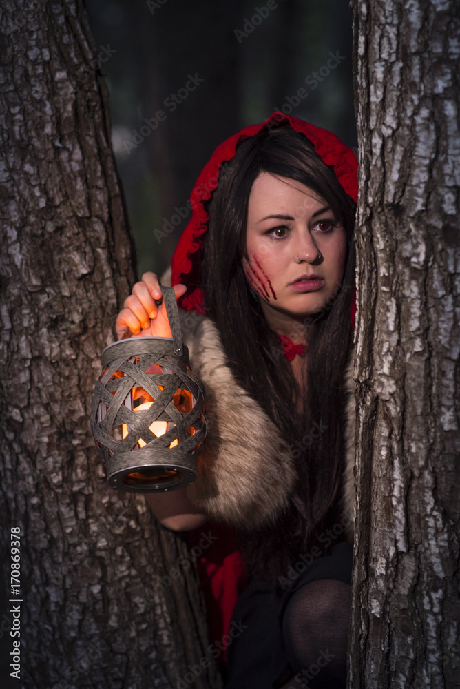 Little Red Riding A slightly darker take on the character where she is the evil one hunting the wolf for its skin. Female model with black hair, forest scene Stock Photo