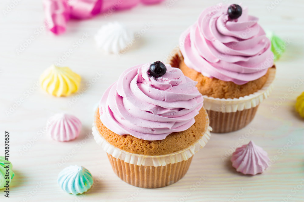 Closeup of cupcakes with vanilla, berries, pink and white cream, chocolate and sprinkles on wooden background. Selective focus. Sweet dessert tasty food concept muffin. Closeup of cupcakes with vanilla, berries, pink and white cream, chocolate and sprinkles on wooden background. Selective focus. Sweet dessert tasty food concept muffin.