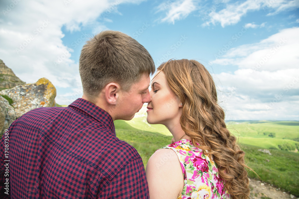 A young married couple reaches for a kiss on the background of a beautiful nature