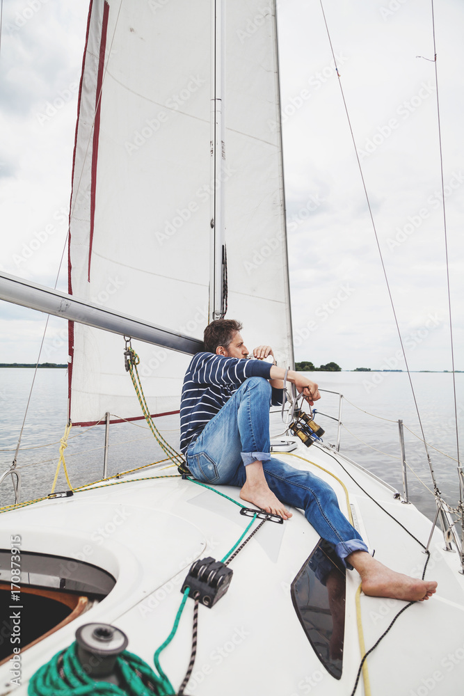 man in striped sweater sits on white sailing yacht man in striped sweater sits on white sailing yacht