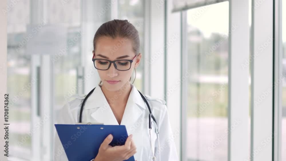 Female doctor with clipboard standing look at camera and smile Female doctor with clipboard standing look at camera and smile