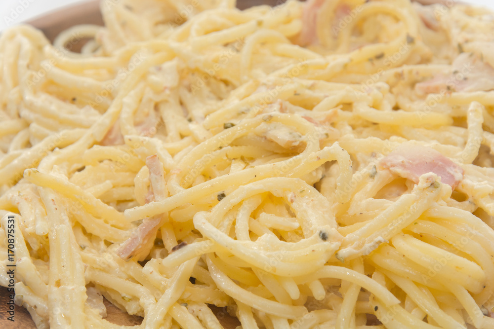 spaghetti carbonara with cream on wooden plate on white background spaghetti carbonara with cream on wooden plate on white background