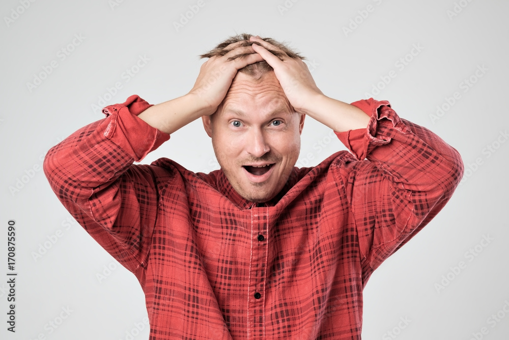 Portrait of young caucasian man in red t-shirt with shocked facial expression, isolated over white background Portrait of young caucasian man in red t-shirt with shocked facial expression, isolated over white background