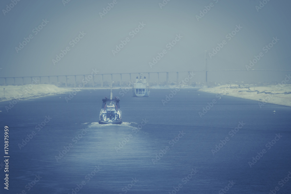 Im Suezkanal - ein Militärschiff und ein Schlepper fahren auf El Qantara und die Mubarak-Friedensbrücke zu