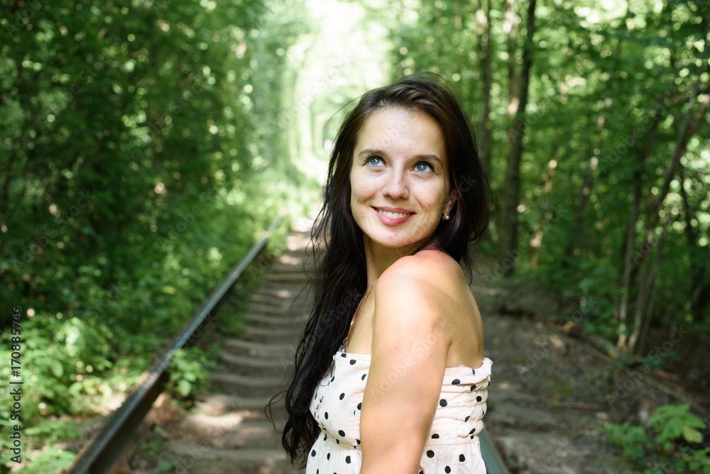 Naklejka premium adorable beautiful young brunette woman in nice elegant dress, posing in nature on a beautiful sunny day on the railway track