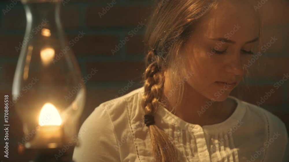 rack focus from an oil lamp to a young woman thinking about something. Period era of late 1800's