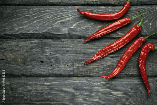 Frame of a red chili pepper of black wooden table. Rustic cuisine. Hot pepper of red color. Overhead view at red chili pepper.