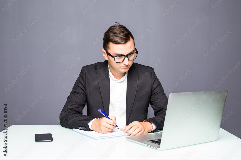Handsome young man working with laptop in office and make notes Handsome young man working with laptop in office and make notes