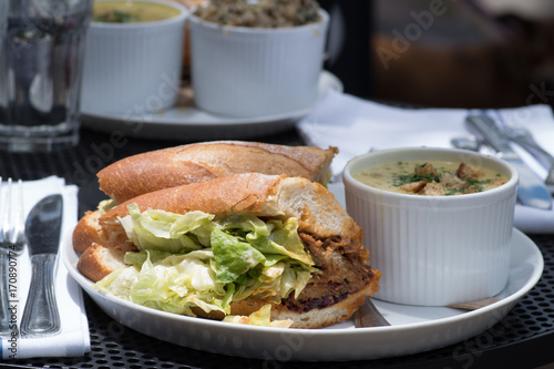 Lunch combo included crispy fresh sandwich with lettuce, sauce and meat and soup on the side served on a table outside.