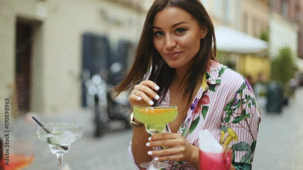 Young pretty sexy girl drinking cold beverage cocktail outdoor in city street cafe, slow motion shot Young pretty sexy girl drinking cold beverage cocktail outdoor in city street cafe, slow motion shot