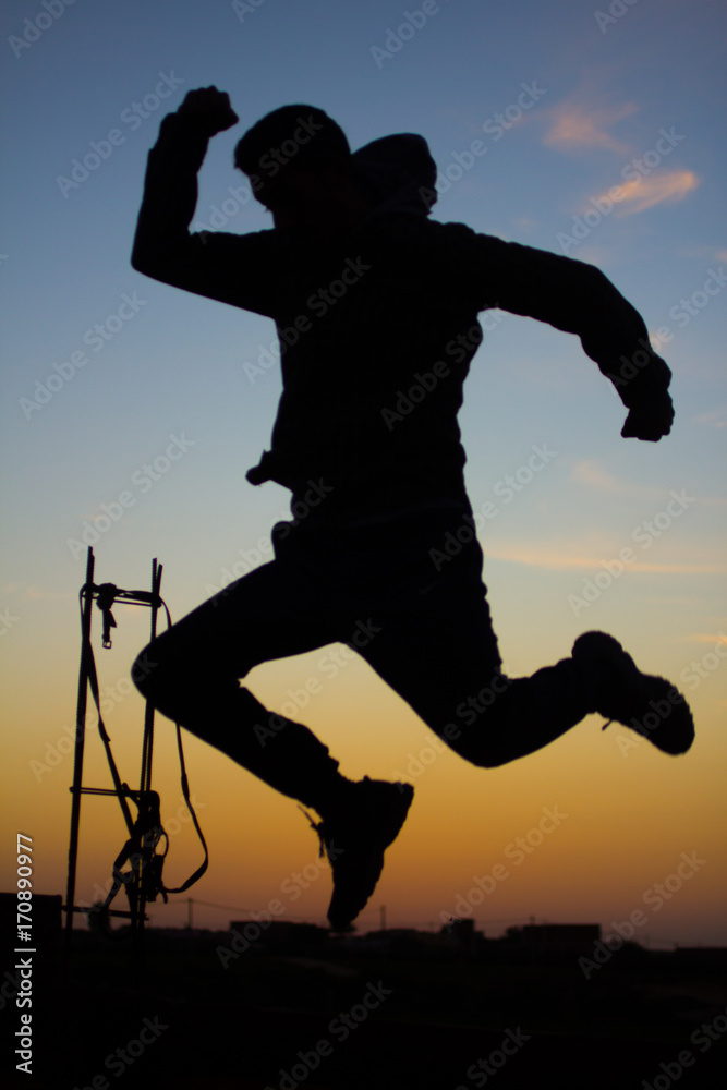 silhouette of man jumping on sunset background