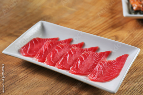 Plate with fresh sliced tuna on wooden table