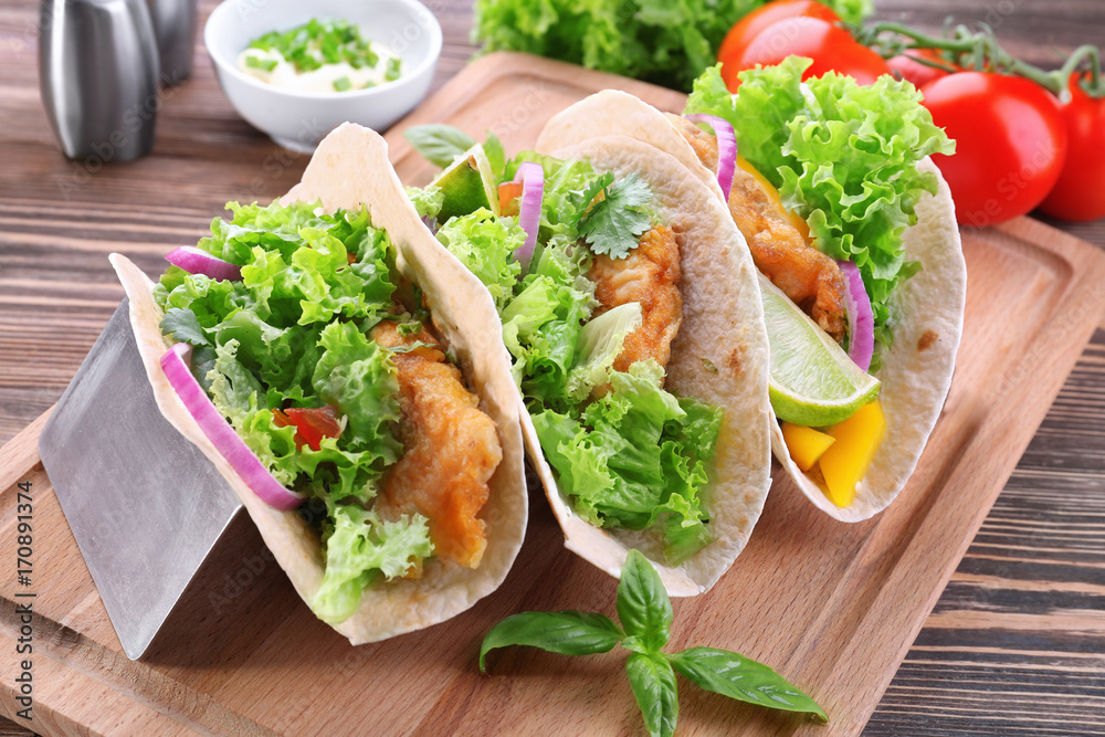 Holder with delicious fish tacos on wooden table