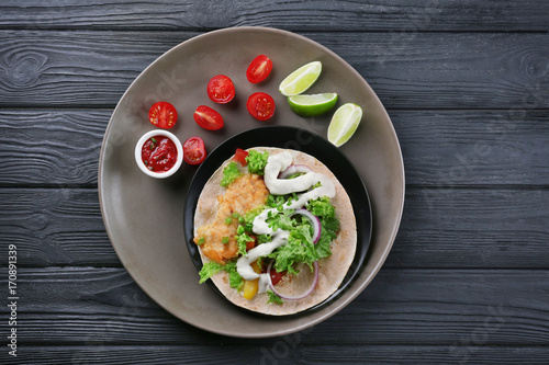Plate with delicious fish taco on wooden table