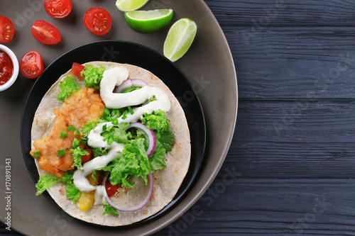 Plate with delicious fish taco on wooden table