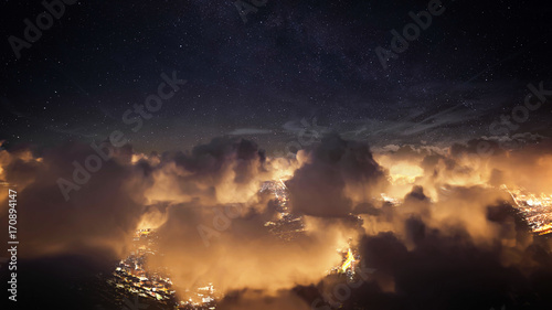 Flying over the deep night clouds with dark sky. Flight through moving cloudscape over night city lights. Perfect for posters, background, digital composition. © railwayfx
