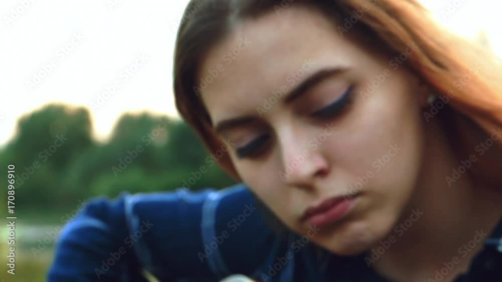 A young beautiful girl, embraced by a creative endeavor and inspired by a forest landscape overlooking the river and simply stunning nature, picks up a new melody for a new song. 4k. Hands close-up A young beautiful girl, embraced by a creative endeavor and inspired by a forest landscape overlooking the river and simply stunning nature, picks up a new melody for a new song. 4k. Hands close-up