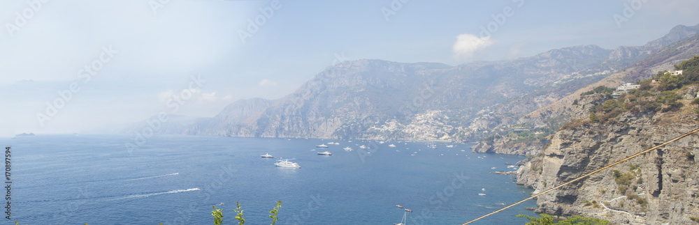 Vista panoramica del borgo di Positano, famosa località turistica e balneare in costiera Amalfitana. Il paese è costruito a picco sul mare con la mantagna dietro. Le case sono colorate.
