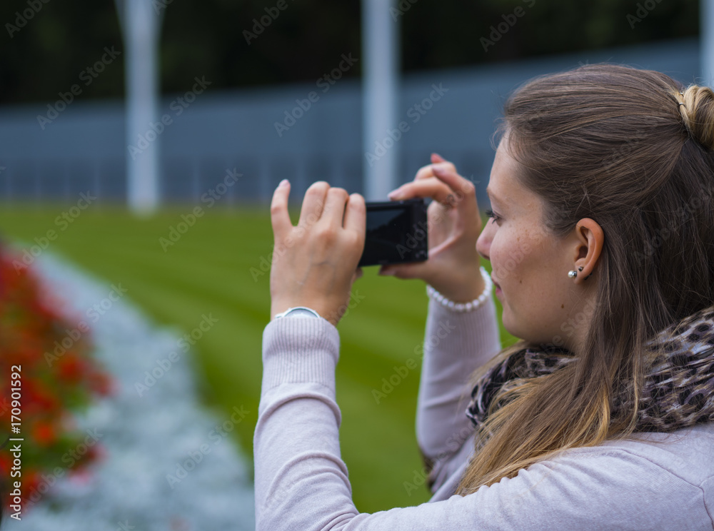 Young girl is taking a photo at a park
