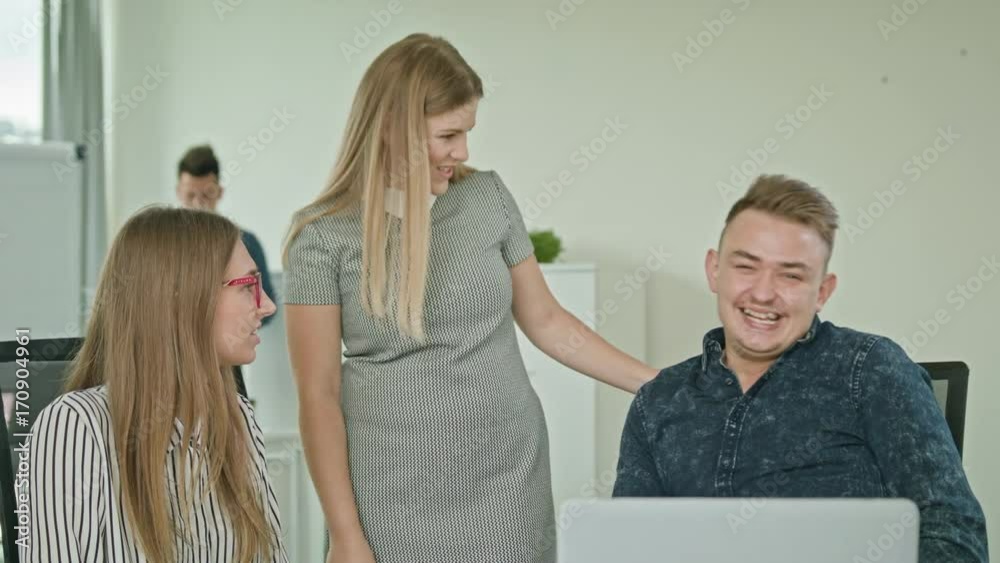two men are working on a laptop in modern start up office a girl brings coffee two men are working on a laptop in modern start up office a girl brings coffee