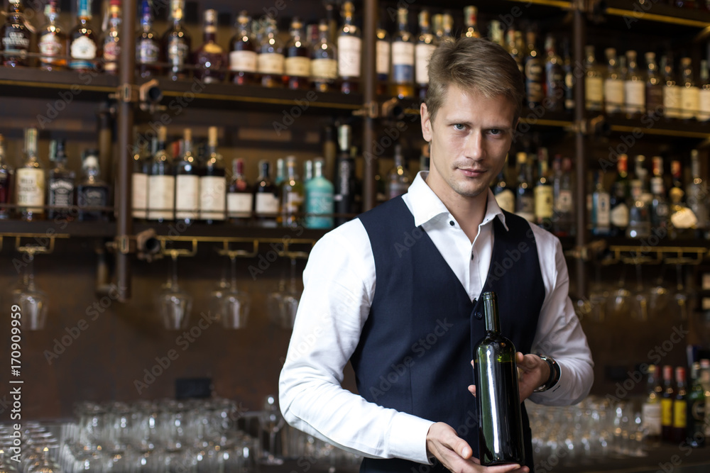 Handsome sommelier man promoting bottle of wine in restaurant, Man present Wine to Customer, Man with Sommelier Concept.
