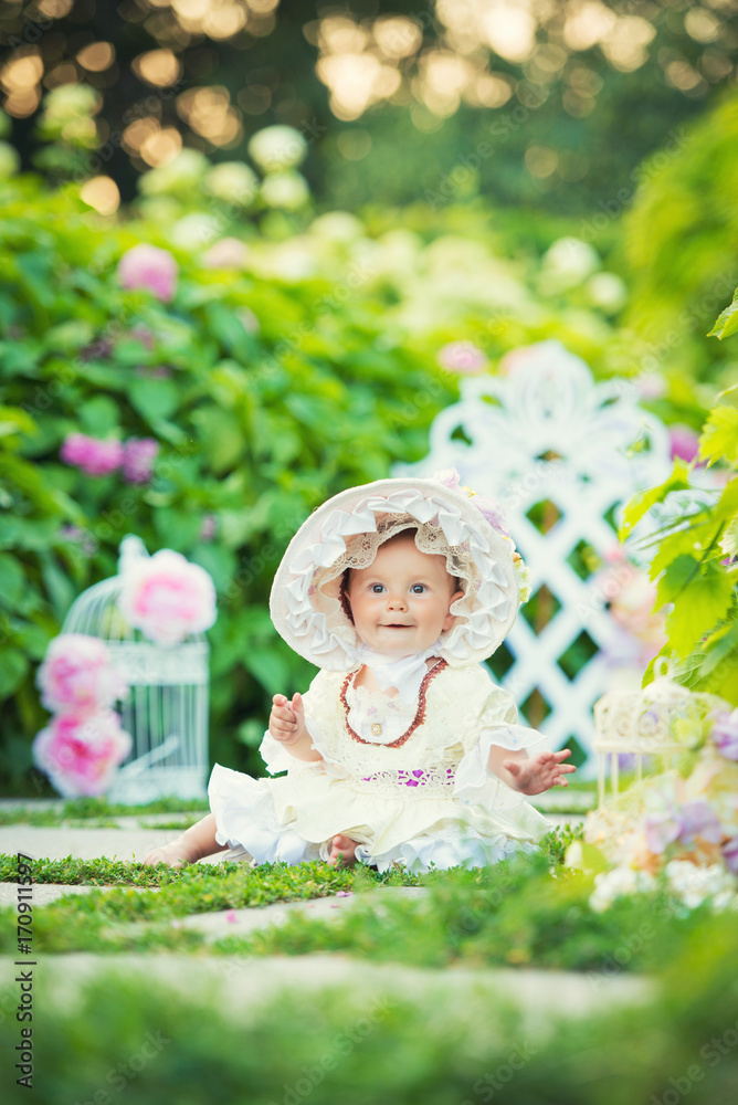 Beautiful little girl in a white dress and hat in a spring garden. Beautiful little girl in a white dress and hat in a spring garden.