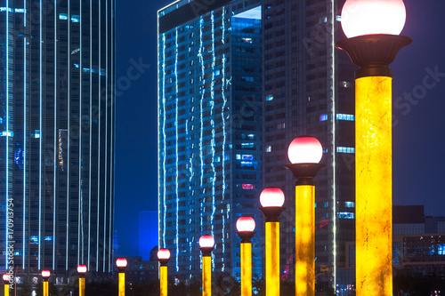 row of lighting street lamps with modern highrises on background,tianjin,china. photo