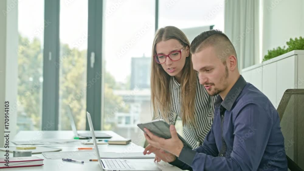Two attractive people discussing ideas using digital tablet Two attractive people discussing ideas using digital tablet