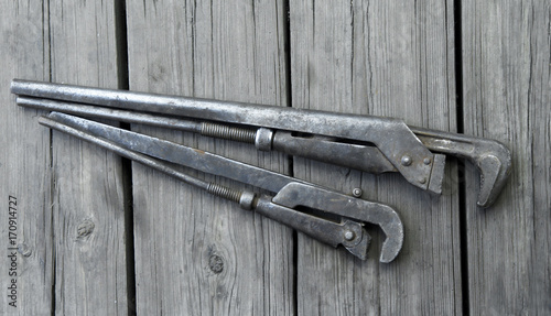 two old plumbing pipe gas swivel wrench on a wooden background. view from above photo