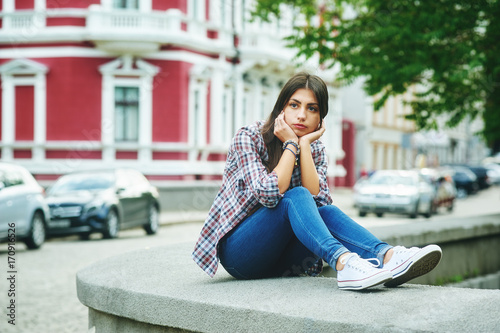 Pensive girl sitting in the city