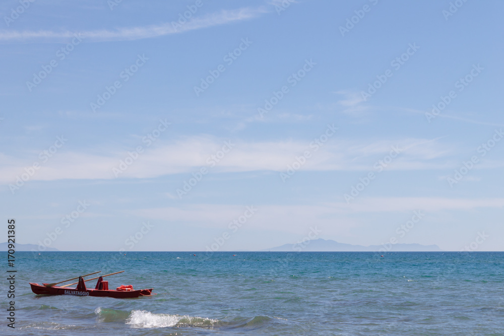 Blue sea and sky, with a red rescue boat in the foreground
