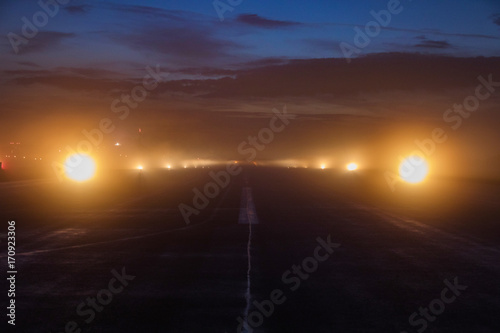 Slika na platnu Empty runway at airport during a foggy evening