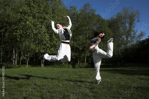 two girl jumping in park