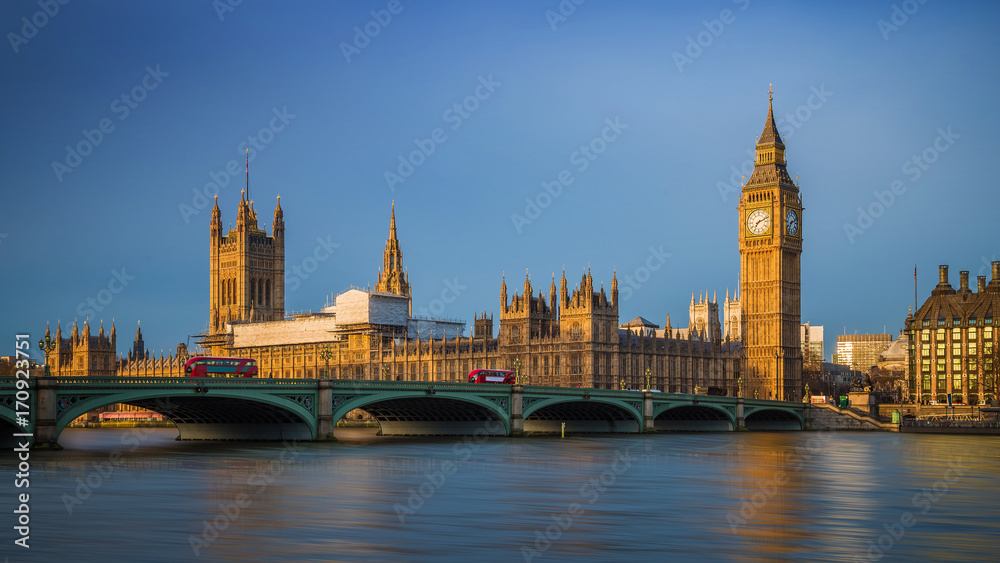 London, England - Traditional red double decker buses on Westminster Bridge with Big Ben and Houses of Parliament at sunrise